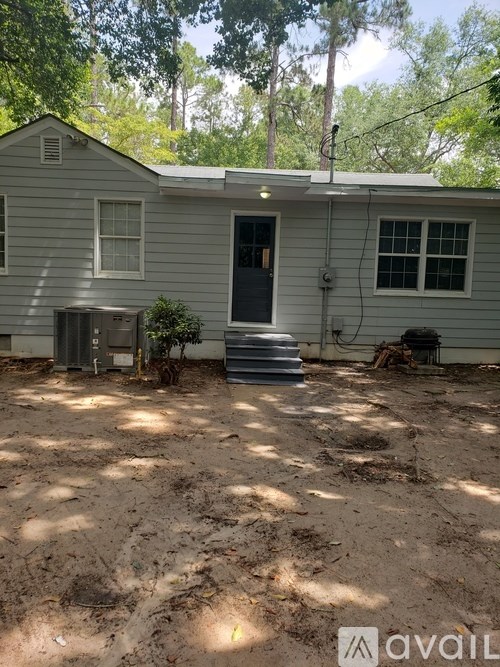 A house with a grey siding and a blue door is for sale.