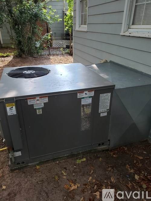 A gray HVAC unit sits outside a house.