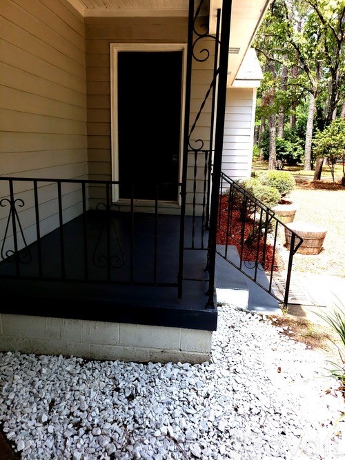 A black door is on the porch of a house.