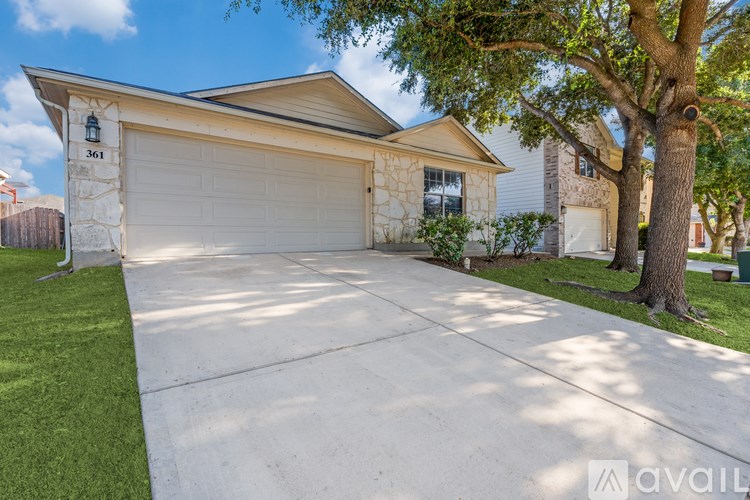 A house with a garage and a tree in front.