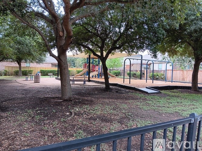 A playground with a slide and swings surrounded by trees.