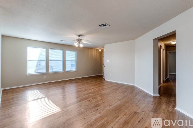 A spacious room with wooden flooring and a ceiling fan.