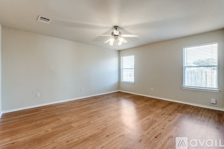 A spacious room with wooden flooring and a ceiling fan.