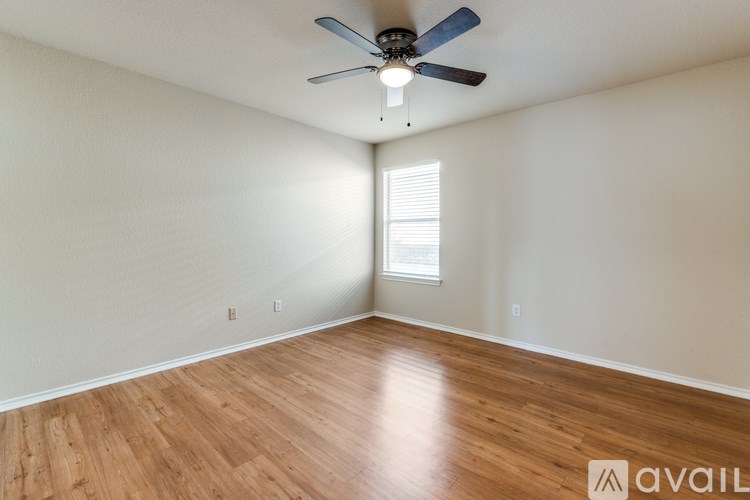 A room with a ceiling fan and wooden flooring.