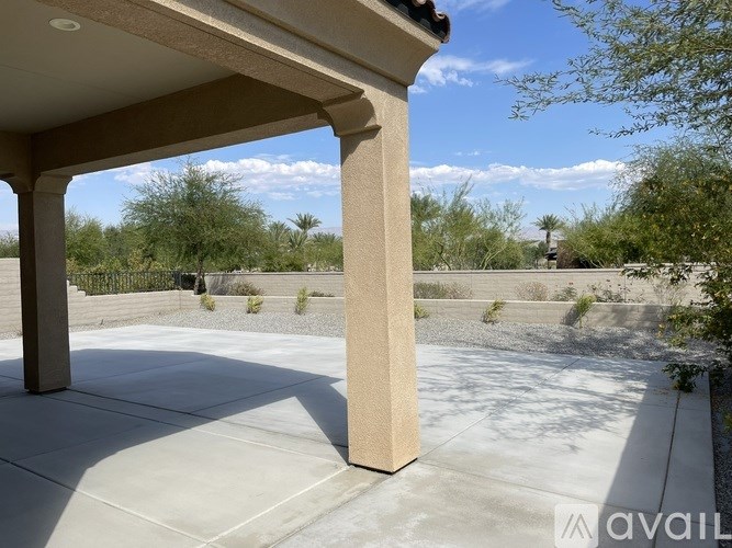 A concrete patio with a white roof and four columns.
