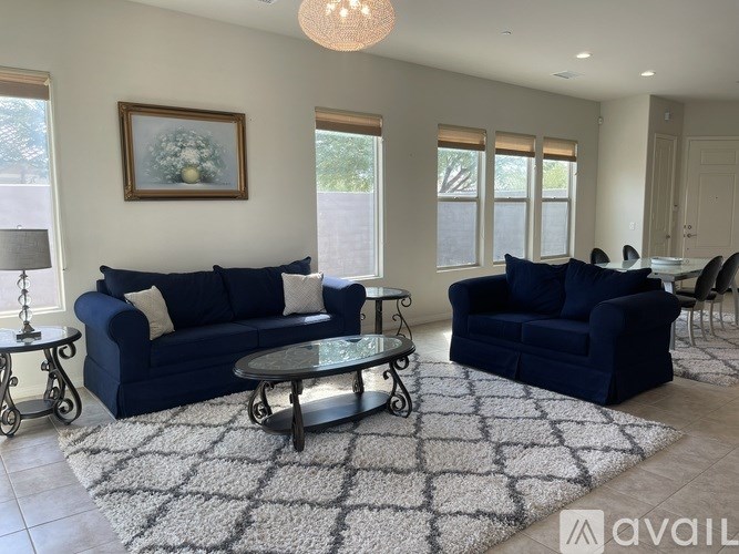 A living room with a blue couch and a glass coffee table.