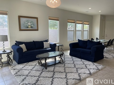 A living room with a blue couch and a glass coffee table.