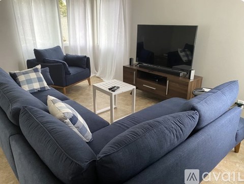 A living room with a blue sofa, a chair, and a television.