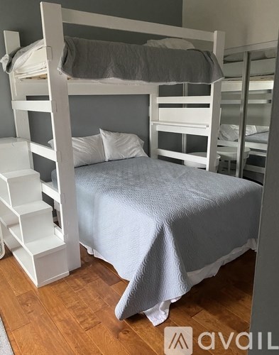 A white bunk bed with a grey blanket and pillow.