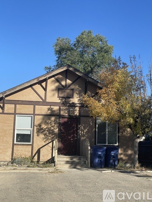 A house with a blue trash can in front of it.