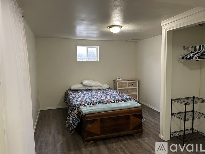 A bedroom with a bed, nightstand, and a window.