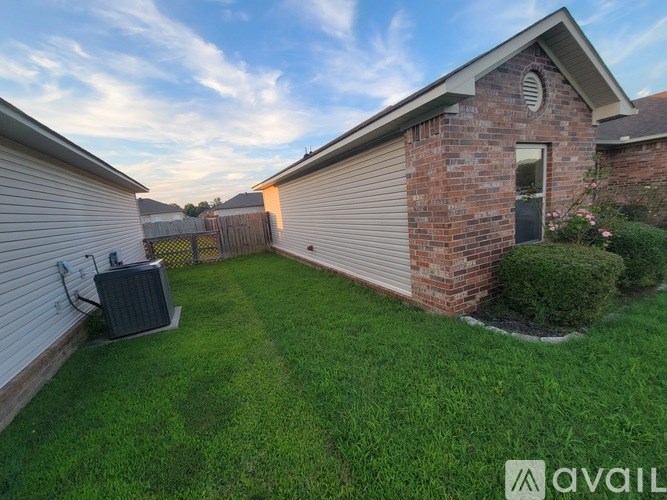 A backyard with a brick house, a green lawn, and a small shed.