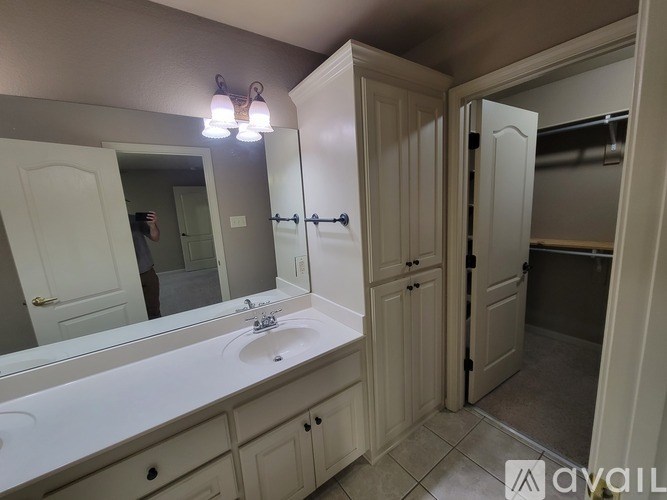 A bathroom with a sink, mirror, and cabinets.