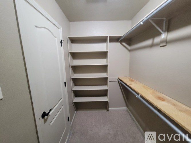 A white door is on the left of a set of shelves in a room.