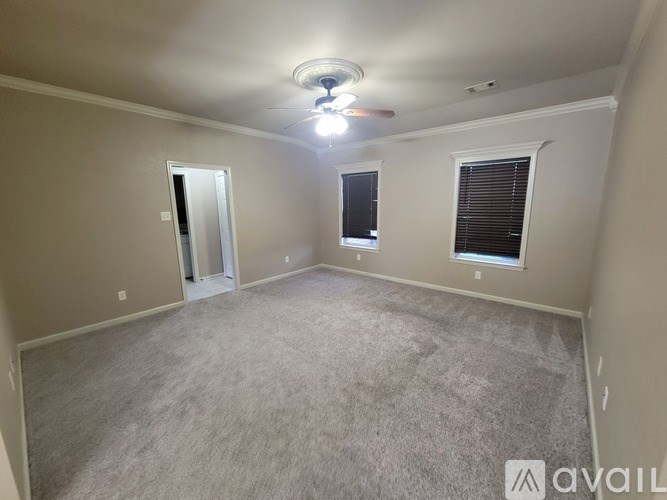 A room with a carpeted floor, a ceiling light, and a window with blinds.