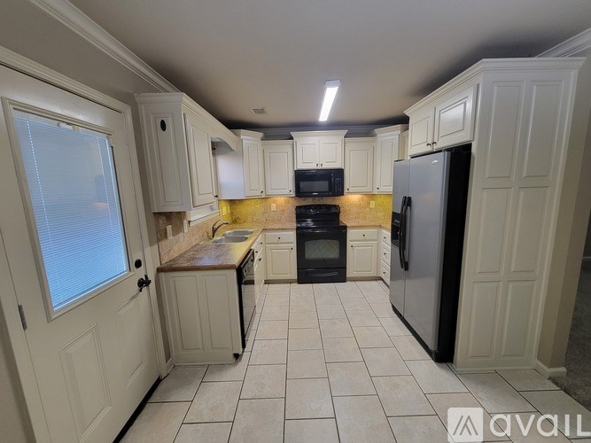 A kitchen with white cabinets and a black refrigerator.