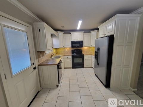 A kitchen with white cabinets and a black refrigerator.