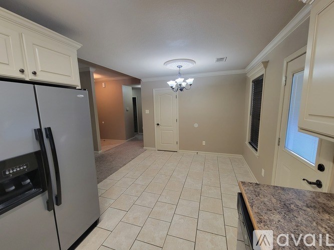 A kitchen with a refrigerator, cabinets, and a countertop.