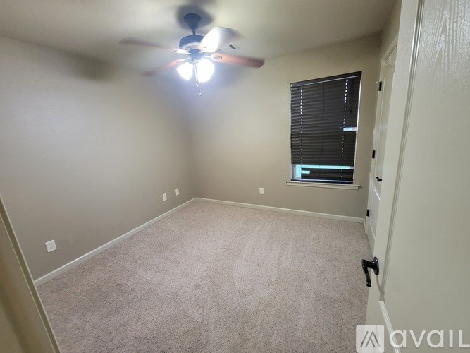 A room with a ceiling fan and carpeted floor.
