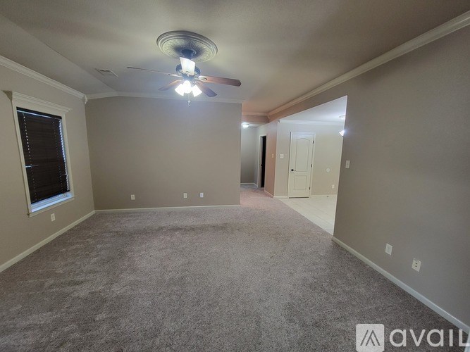 A spacious room with a ceiling fan and carpeted floor.