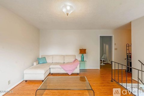 A living room with a white couch and a glass table.