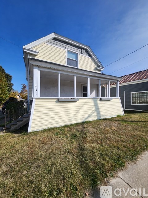 A house with a white front porch and a brown roof.