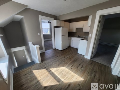 A kitchen with white appliances and wooden floors.