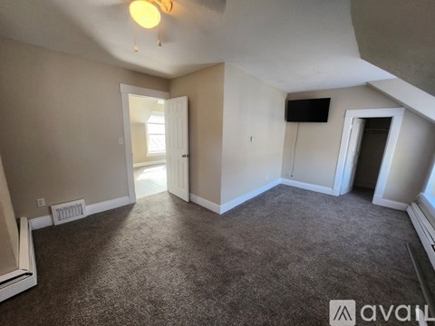 A room with carpeted floor and a window on the right side.