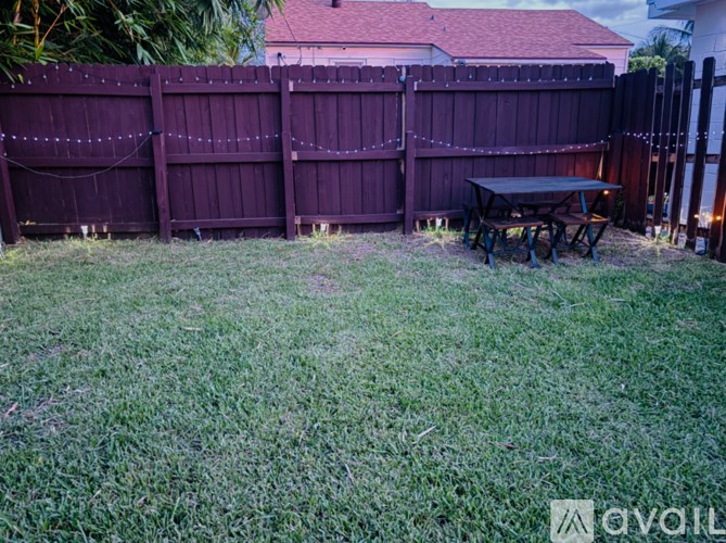 A backyard with a wooden fence and a picnic table.