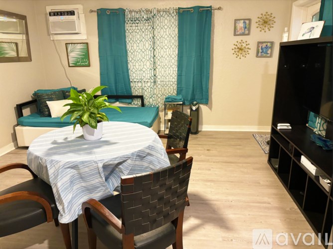 A room with a bed, a table with chairs, and a television.