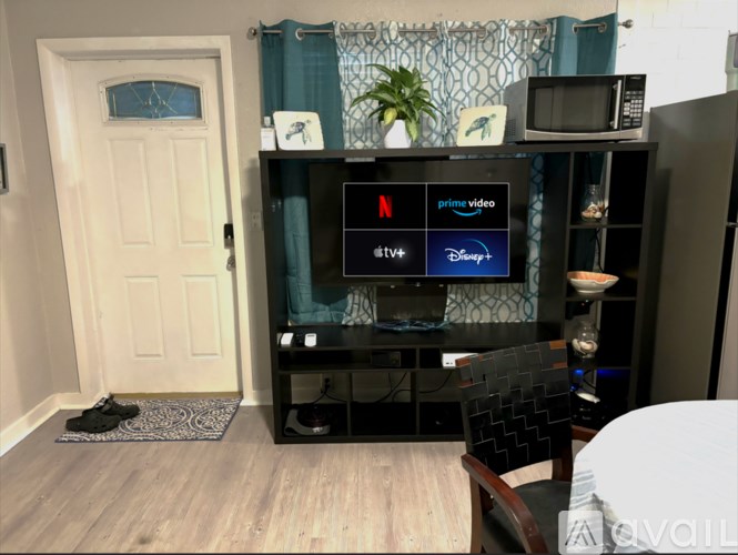 A black entertainment center with a flat screen TV displaying logos for Netflix, Prime Video, and Disney.