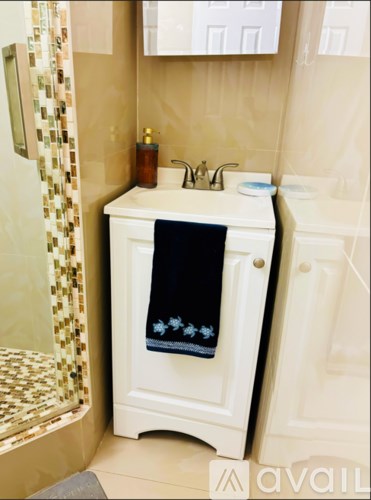 A small white cabinet with a black towel on top of it.