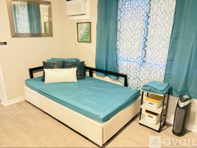 A bedroom with a bed, nightstand, and a window with curtains.