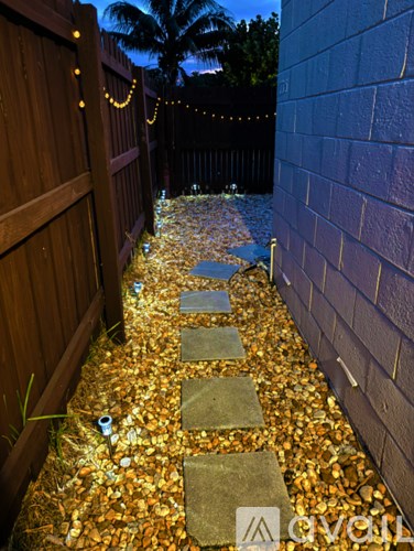A pathway made of stepping stones is lined with yellow leaves.