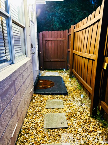A garden pathway with stepping stones and a wooden fence.