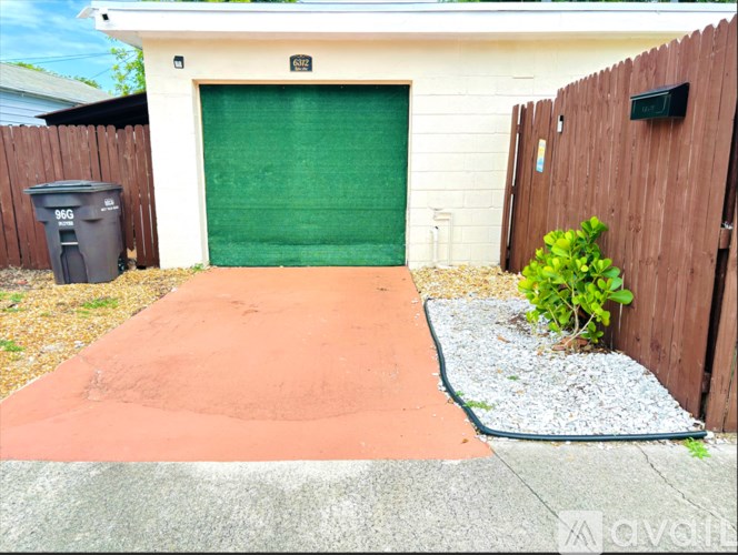 A green garage door is on the left side of a white house.