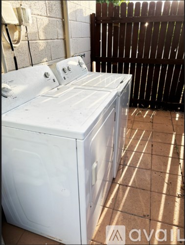 A white washing machine is sitting on a tiled floor.