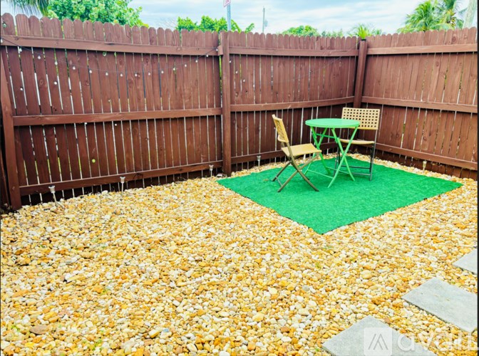 A backyard with a brown fence and a green table and chair set.