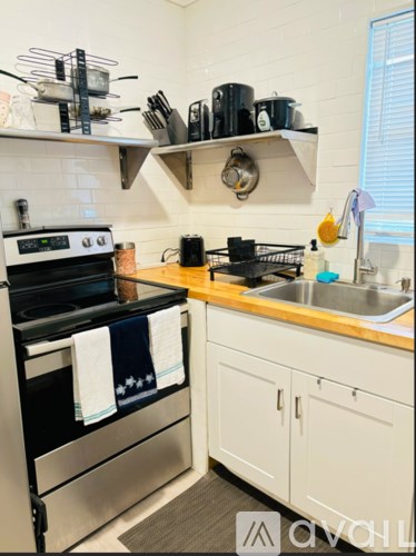 A kitchen with a stove, sink, and cabinets.