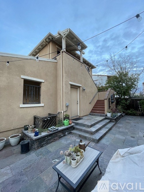 A patio area with a table, chairs, and potted plants.