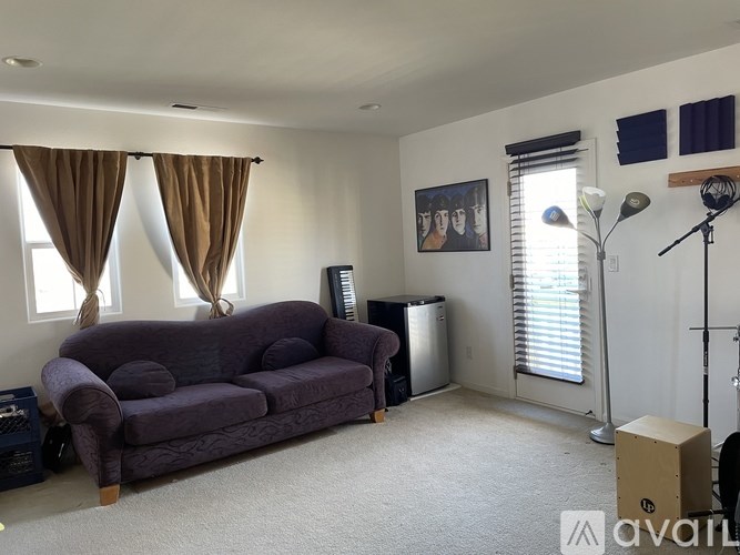 A living room with a purple couch and a painting on the wall.