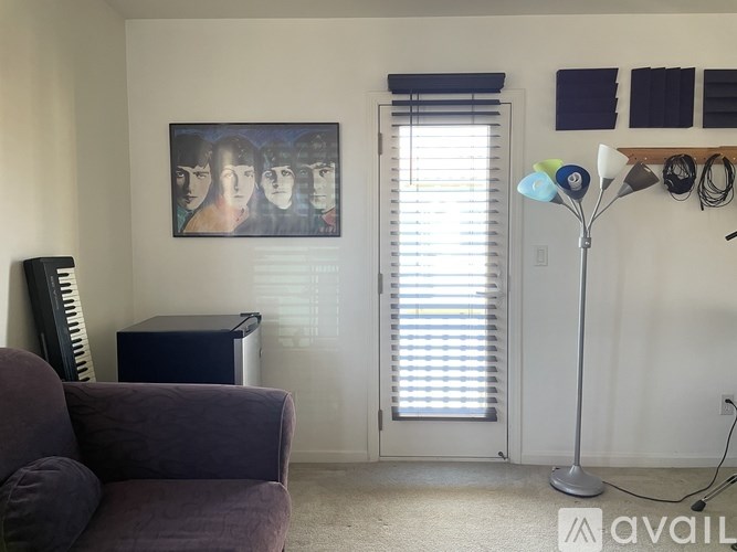 A living room with a purple couch, a picture on the wall, and a floor lamp.