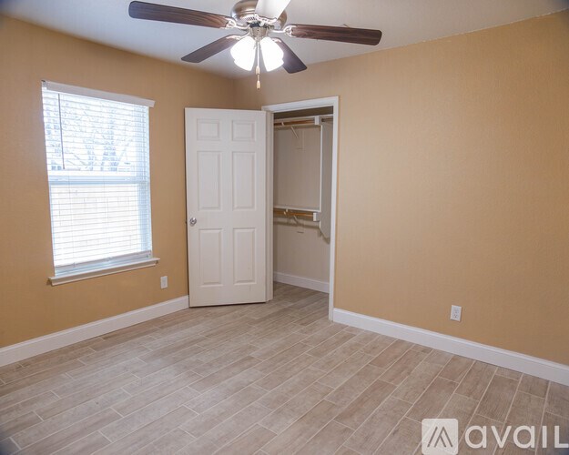 A room with a ceiling fan and a door leading to another room.