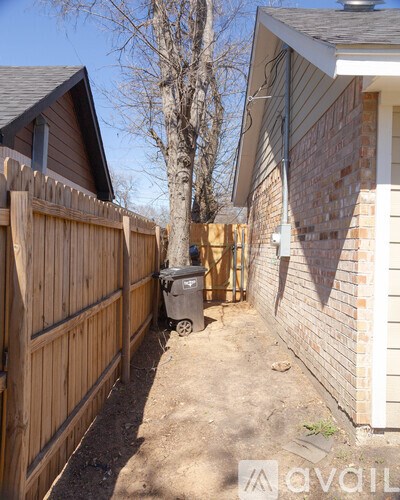 A backyard with a wooden fence and a trash can.