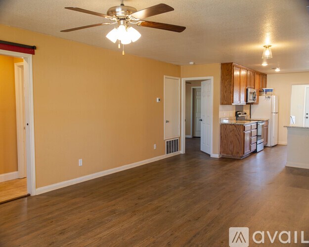 A spacious living room with a ceiling fan and hardwood floors.