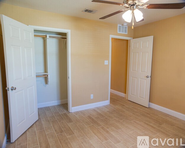 A room with a ceiling fan and two doors, one of which is open.