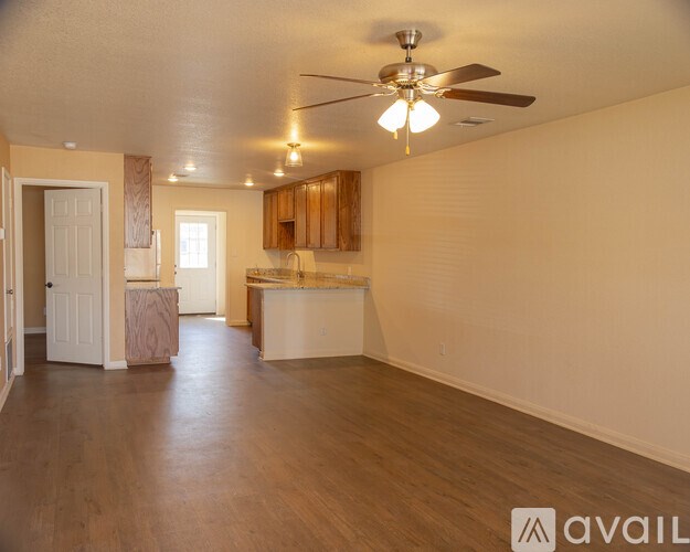 A spacious living room with a kitchen in the background.