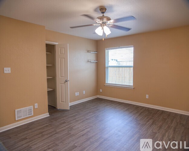 A room with a ceiling fan and a window with blinds.