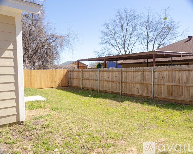 A backyard with a wooden fence and a house.