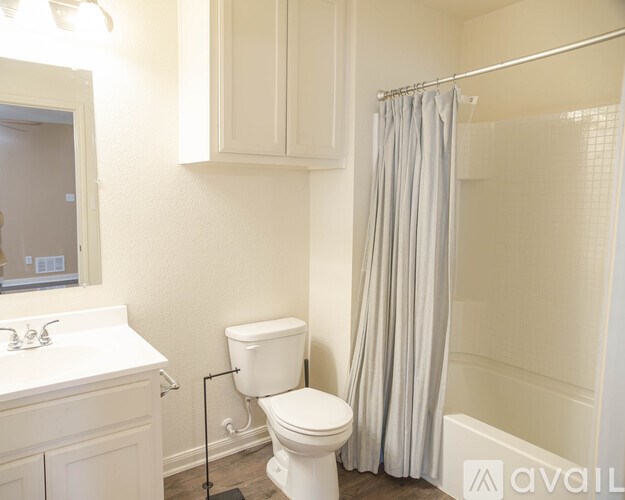 A white toilet in a bathroom with a white sink and a shower curtain.